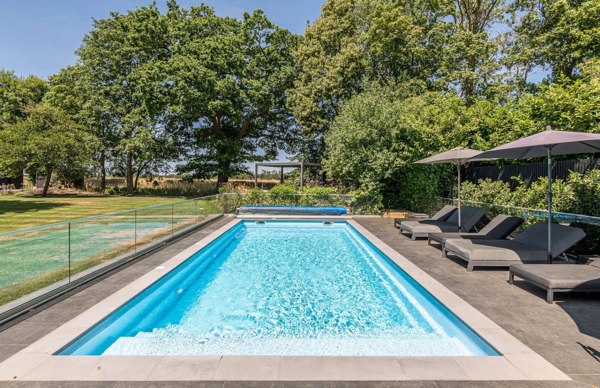 Stunning luxury outdoor swimming pool location with clear blue water and an integrated solar cover track, via Love Locations.