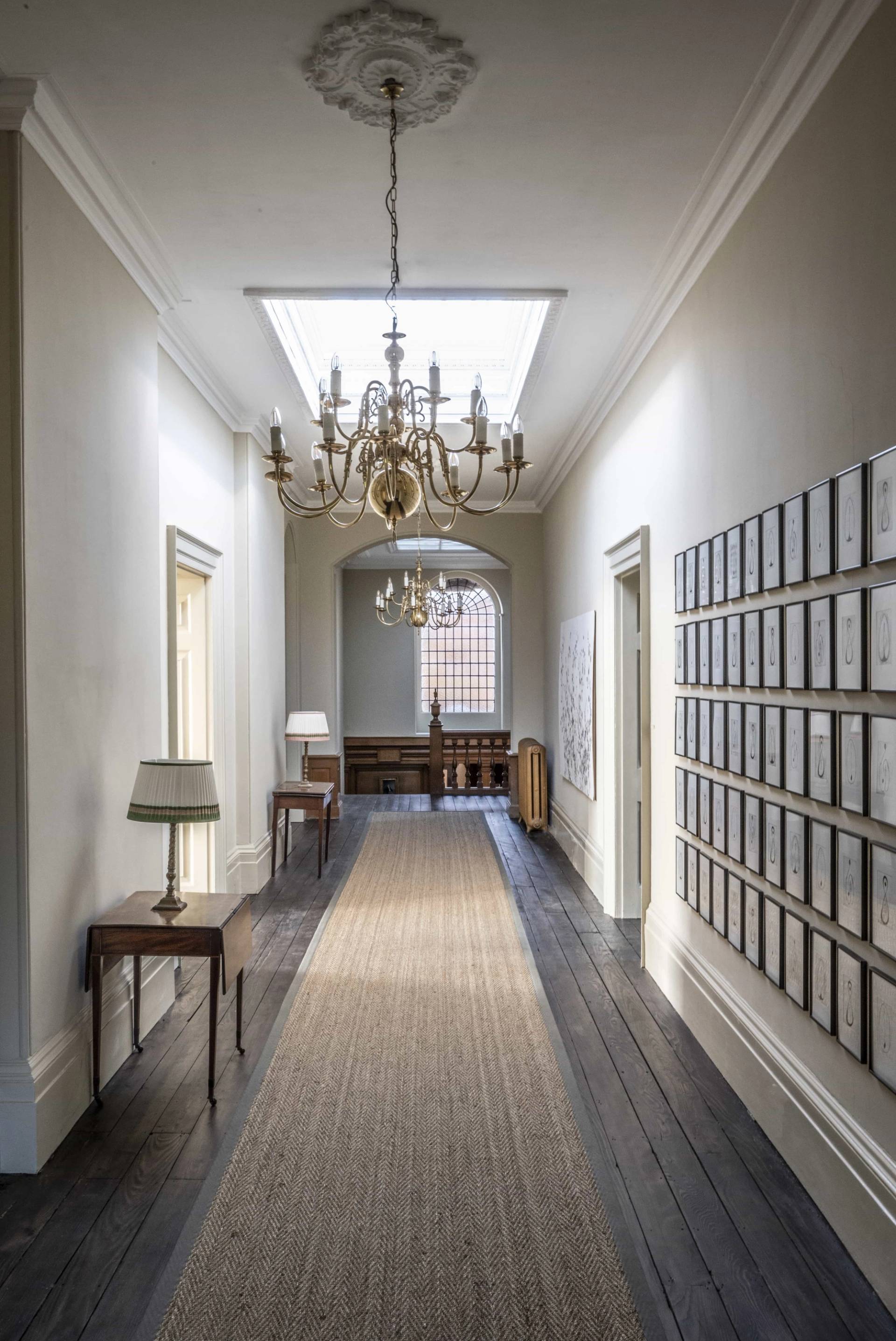 Light-filled upper corridor with a crystal chandelier and gallery frame displays, ideal for corporate or editorial shoots, Love Locations.