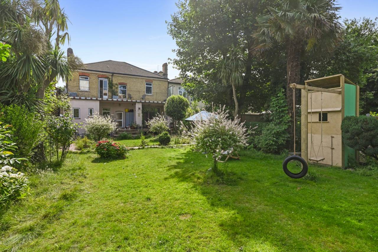Lush green back garden grounds with mature trees and perimeter garden beds in East London, Love Locations E7.