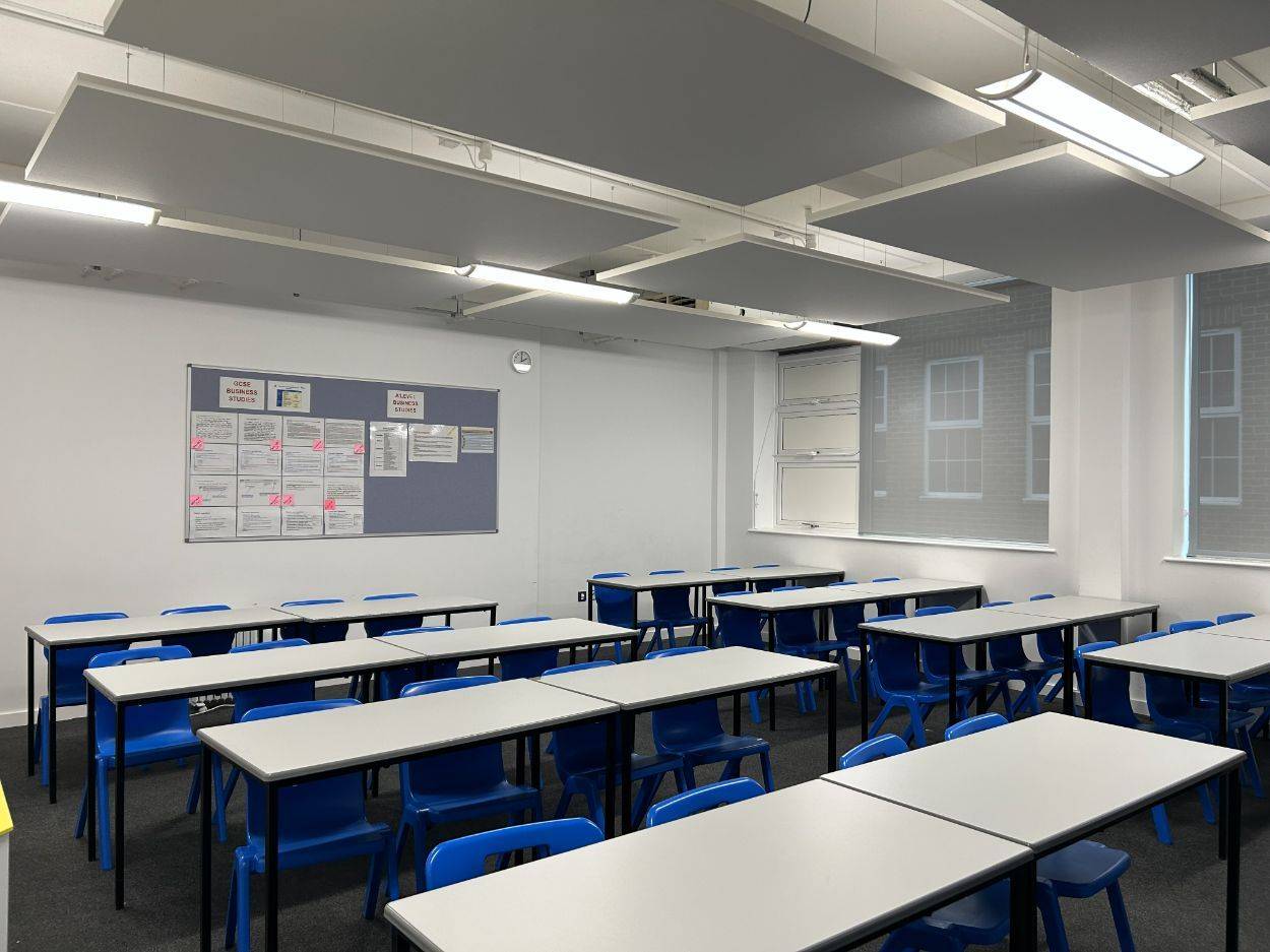 Modern secondary school classroom shoot space with grey tables, blue chairs, whiteboards, and suspended ceiling lights via Love Locations.