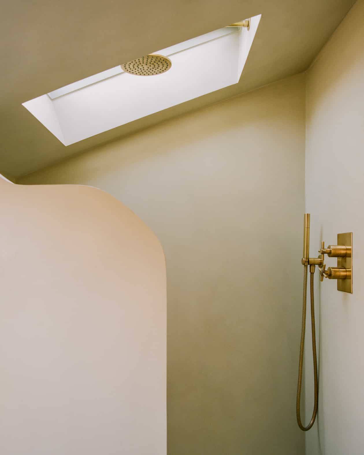 Minimalist clay plaster wet room shower space with brass fittings and an overhead skylight, Love Locations SW4. 🧱