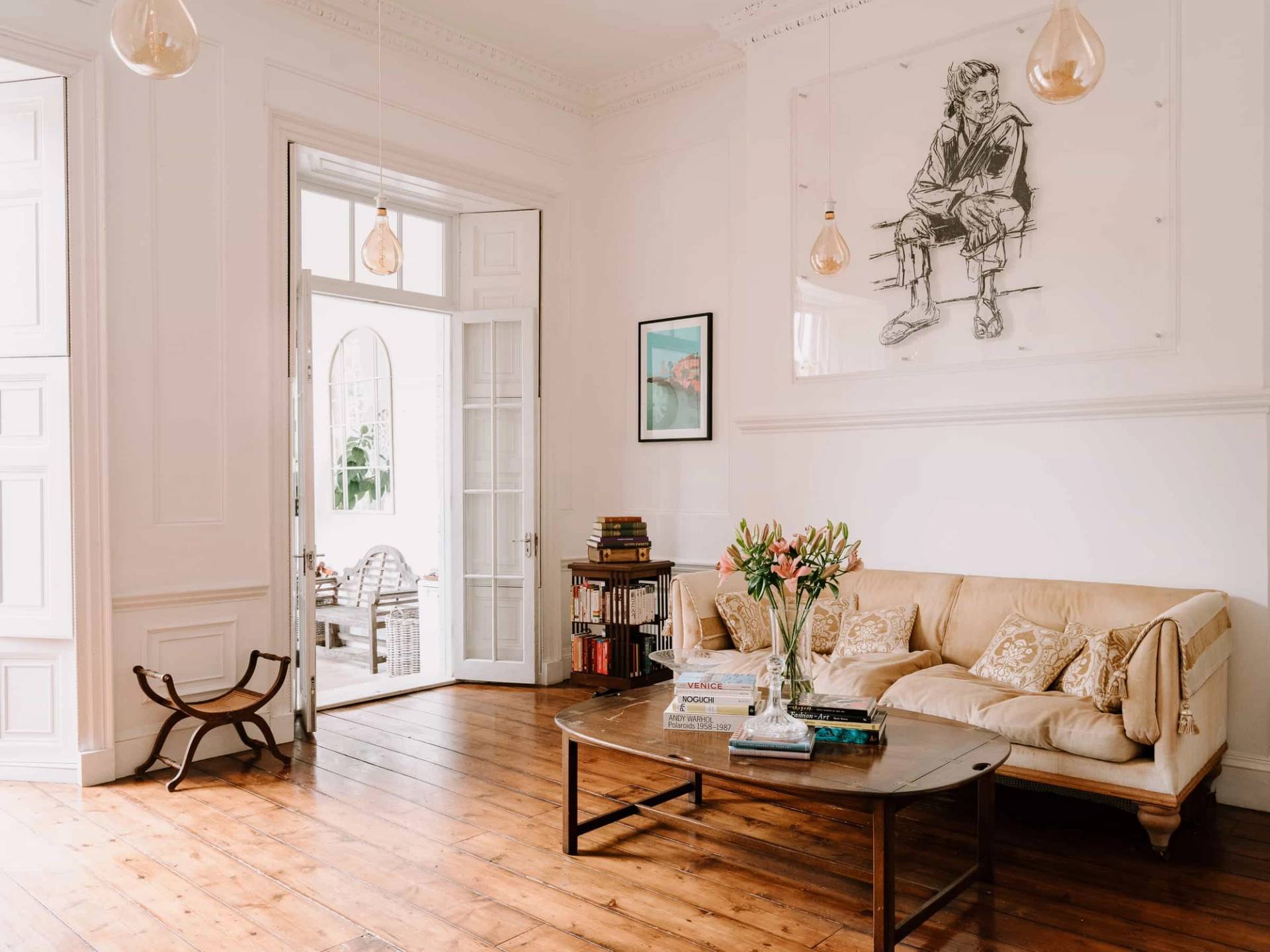 Light-filled reception lounge with beige sofa, circular glass coffee table, and glazed garden patio doors, Love Locations RG42.