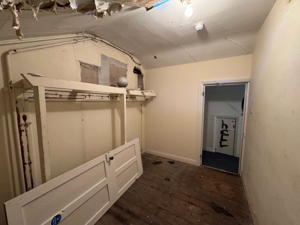 Run-down storage room with exposed timber floorboards and detached white panel doors sitting loose, Love Locations.