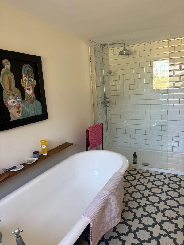 Roll-top clawfoot bathtub set beside a tiled walk-in shower enclosure in a rustic farm cottage, Love Locations BN8.
