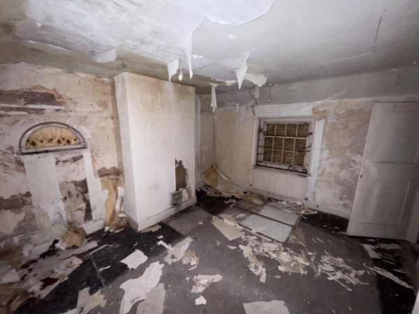 Dilapidated Victorian fireplace room with large sheets of peeling ceiling plaster hanging down, spooky film set hire through Love Locations.