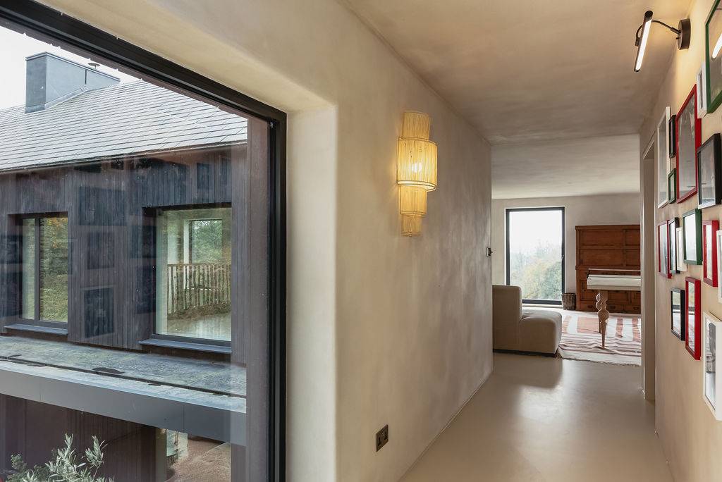 Microcement corridor with recessed door frames and warm brass wall sconce lighting, Love Locations GU32.