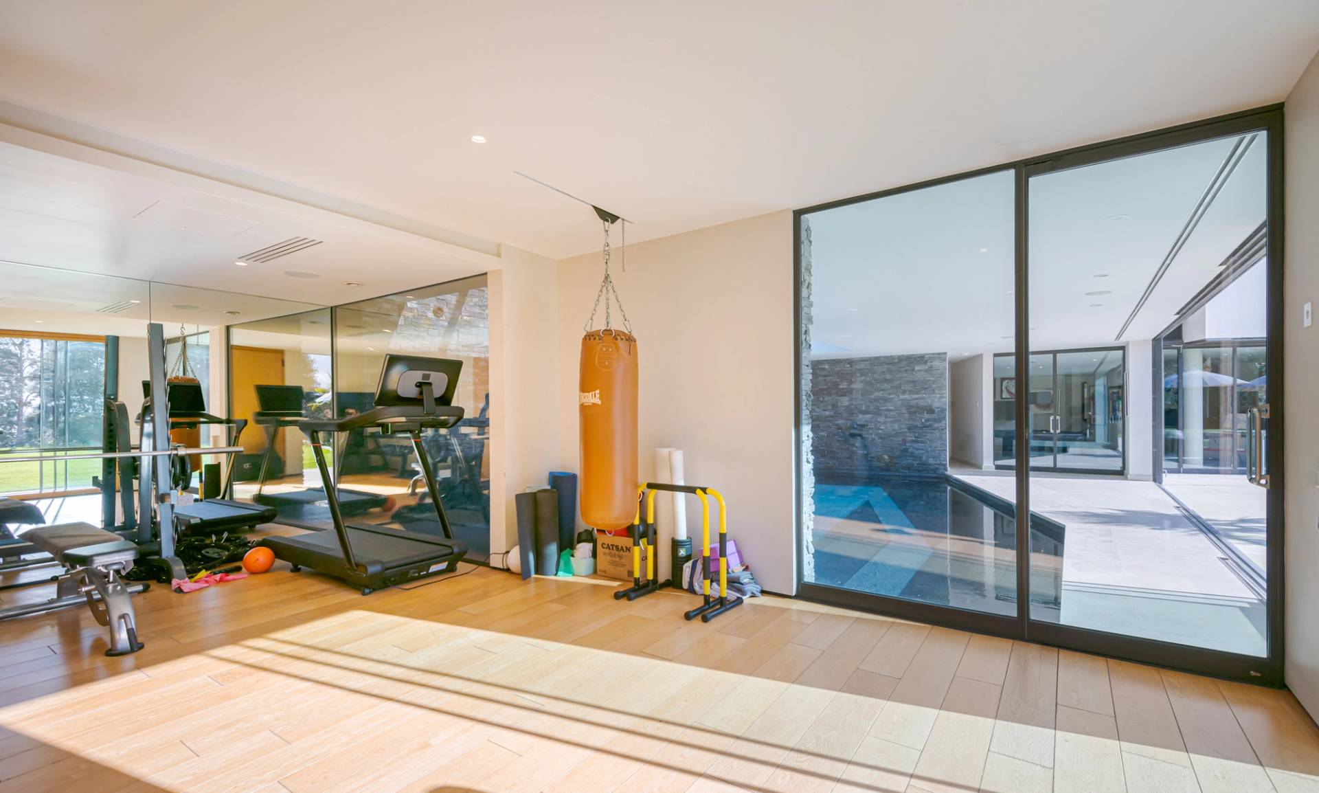 Private home gym workout room featuring treadmill, leather punching bag, and direct indoor pool access, ideal for fitness brands, Love Locations KT2.