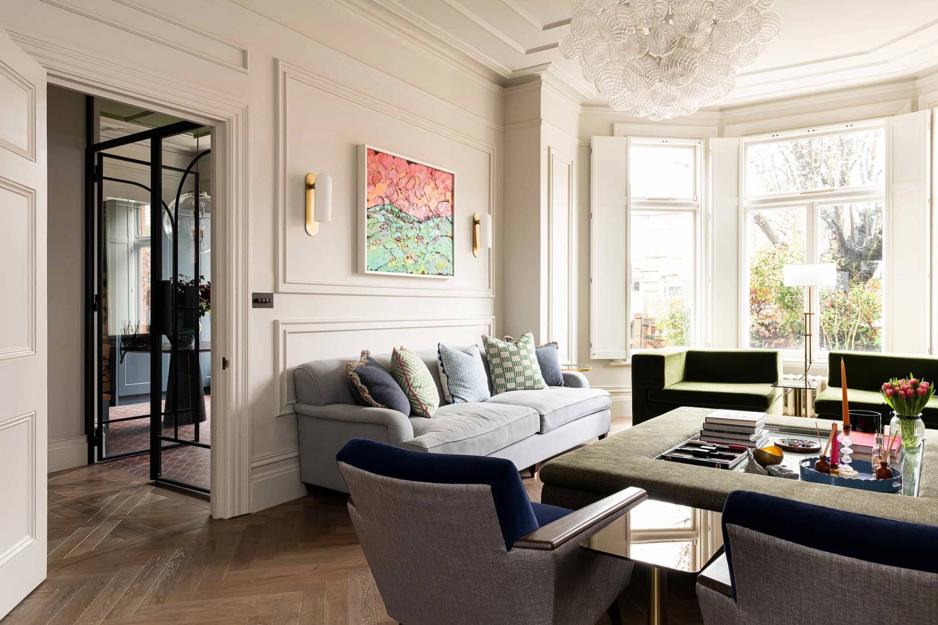 Formal living room corner with grey sofa, wall panelling moulding, round brass wall mirror, and high ceilings, perfect for interior design features, Love Locations NW6.