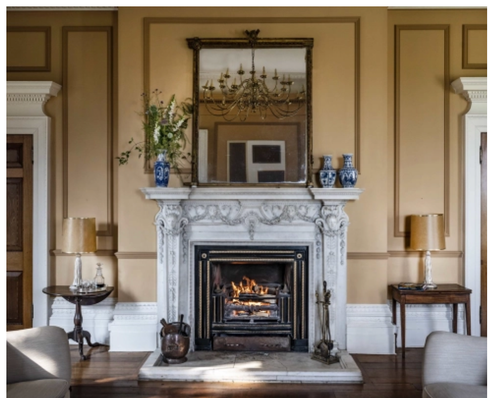 Elegant reception room at Keythorpe Hall featuring an ornate marble fireplace, heritage panelling, chandelier and period architectural details.