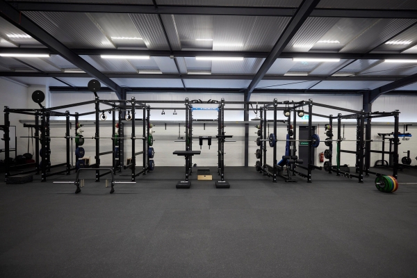 Symmetrical layout of heavy-duty steel power racks and strength training rigs inside a spacious fitness studio in Hampshire, SO23, Love Locations.