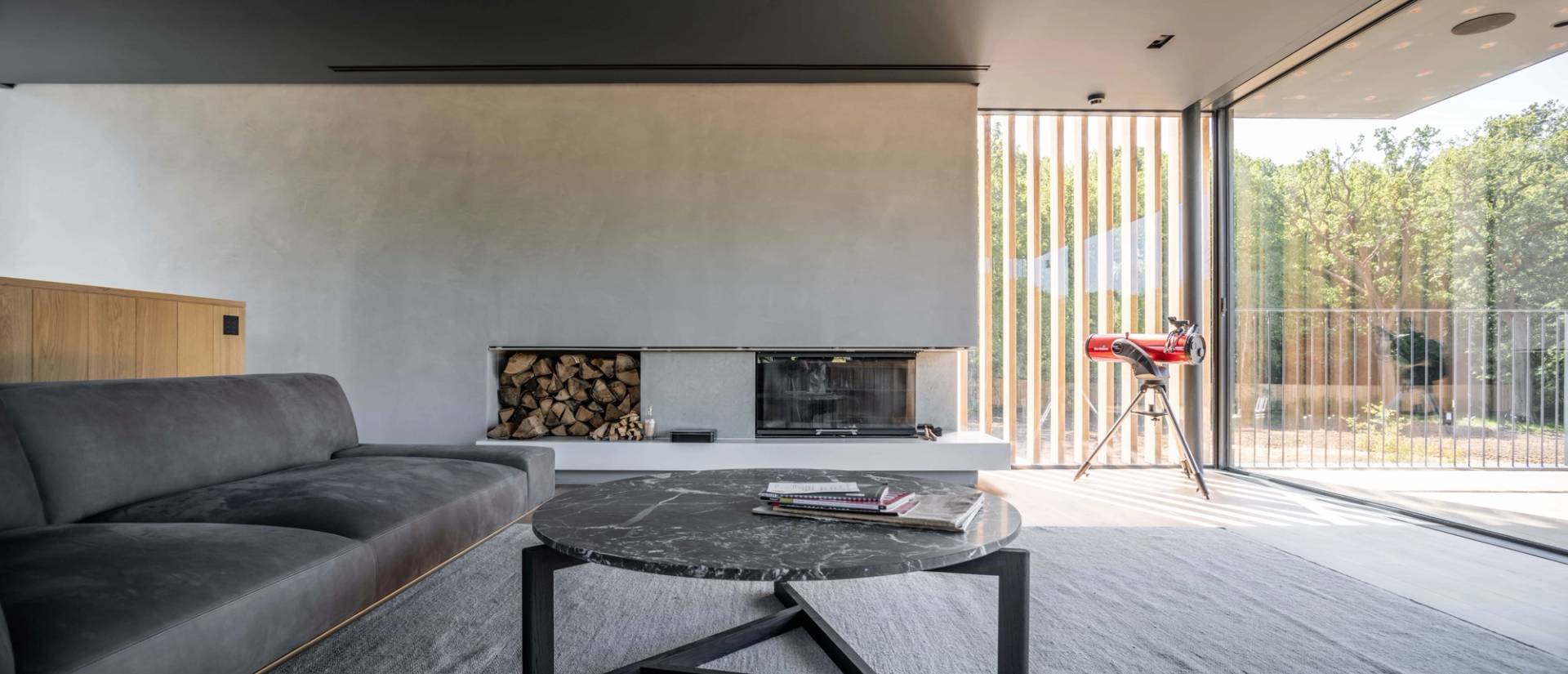 Modern minimalist fireplace setup featuring a sleek concrete hearth, dark marble coffee table, and neatly stacked firewood, Love Locations Fryerning.