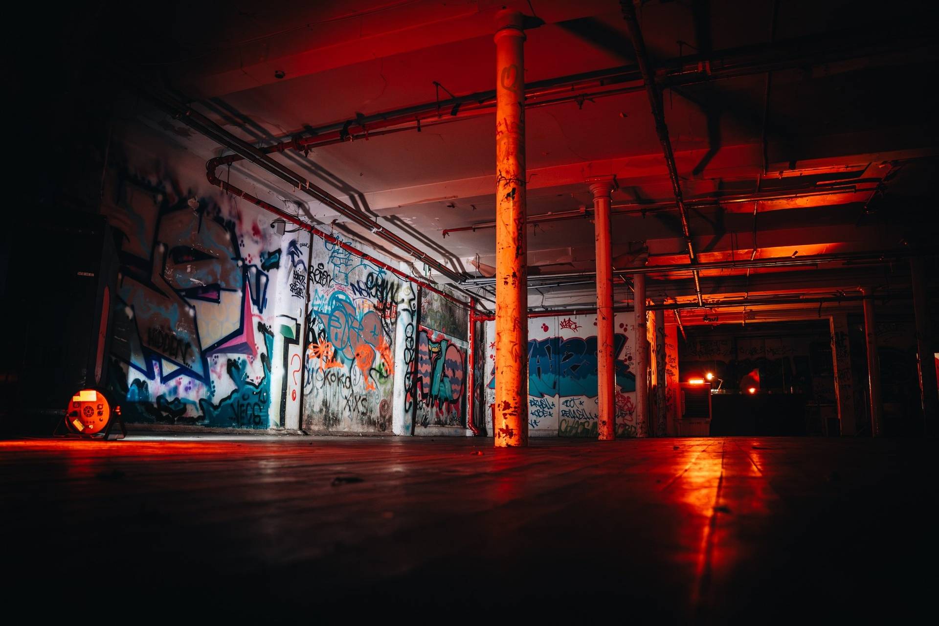 Atmospheric underground event space with colorful graffiti artwork on concrete walls and red overhead lights in Manchester M3 through Love Locations.