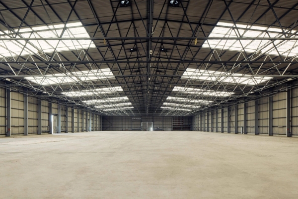 Vast empty industrial warehouse location for hire in Deptford, SE8 featuring exposed steel roof trusses, perfect for large-scale set builds and commercial filming via Love Locations.