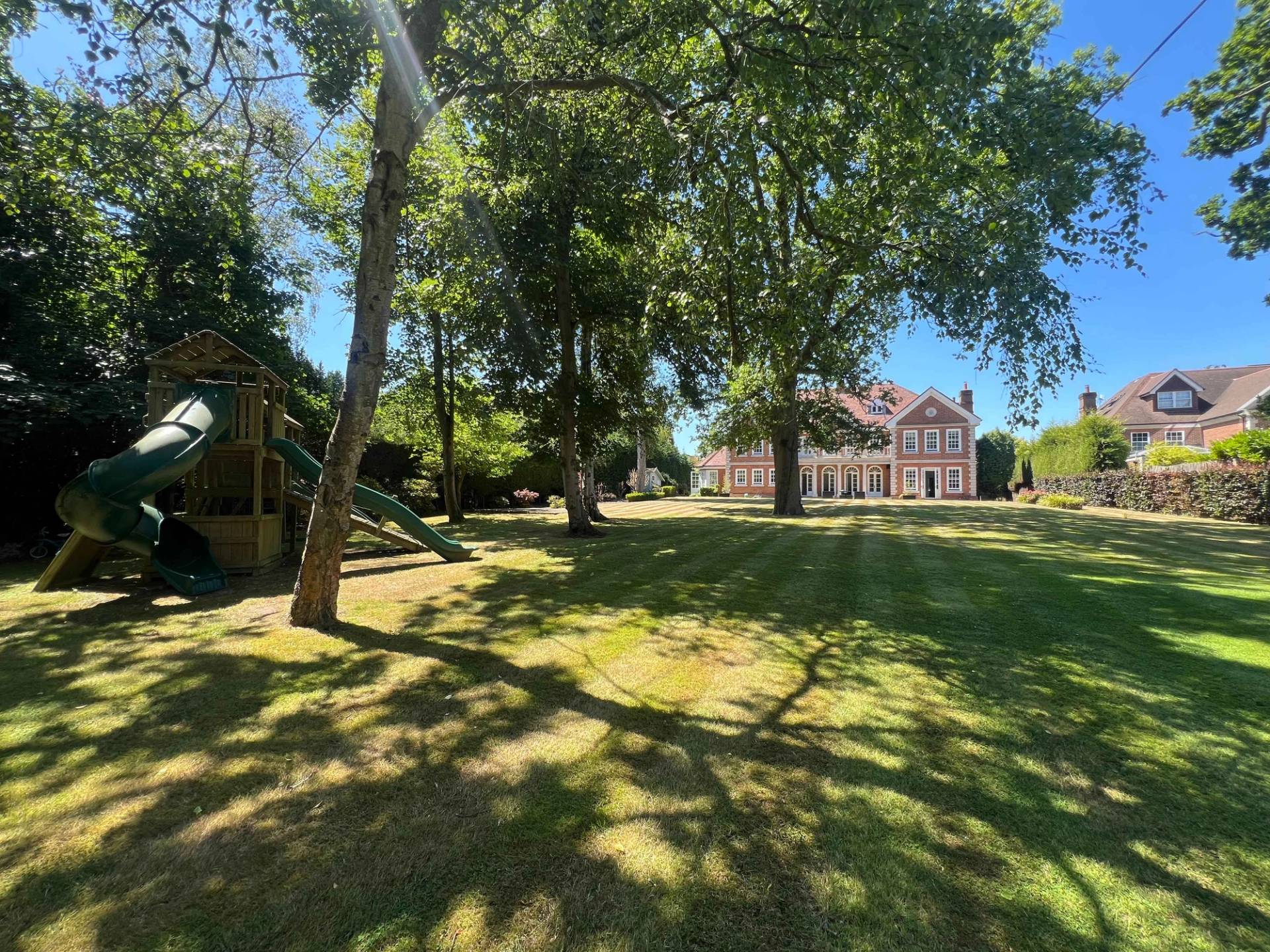Expansive manicured lawn garden surrounded by mature trees on a private Bromley estate, Love Locations BR7.
