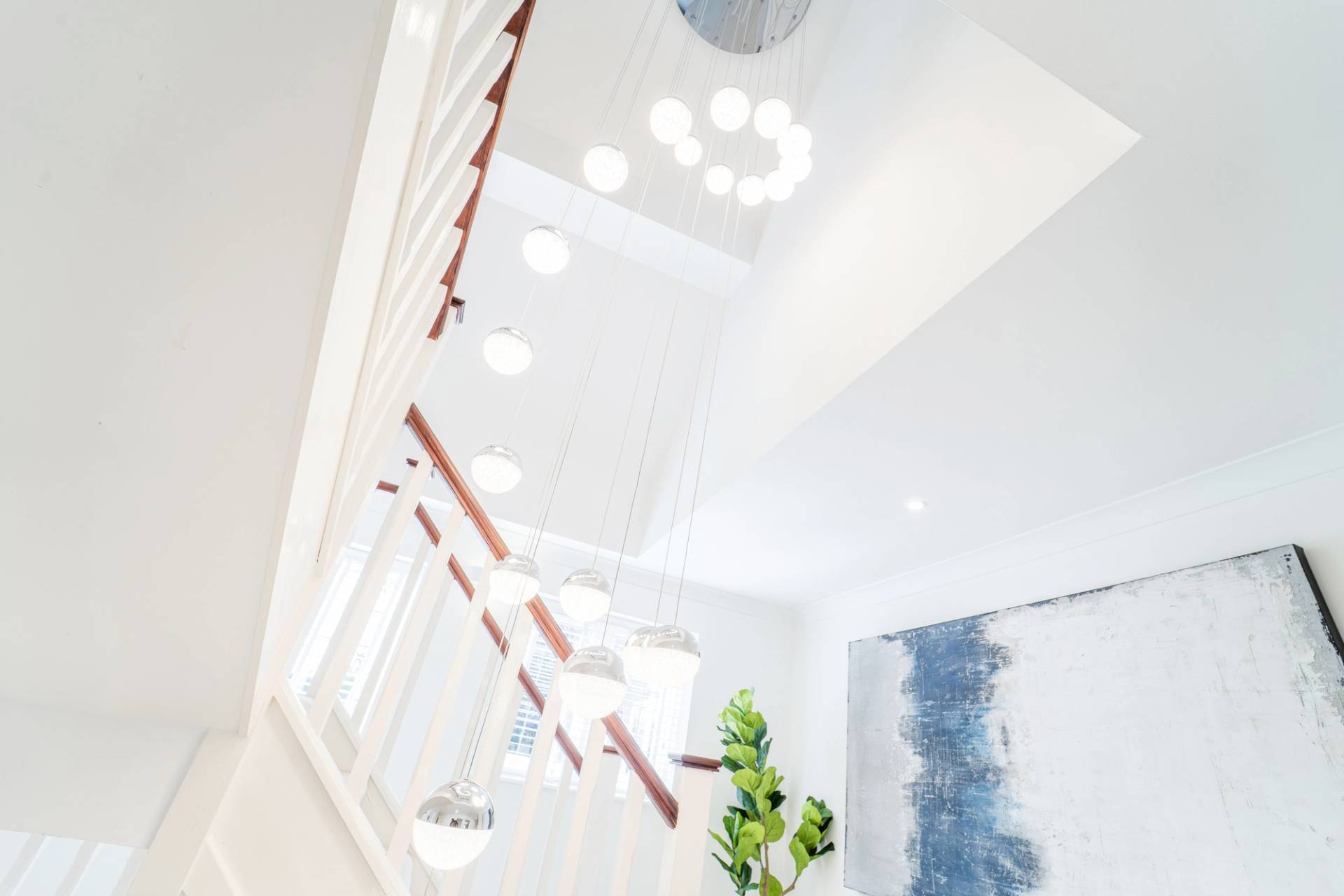 Double-height entrance hall gallery view looking up at a cascading crystal ring chandelier, Love Locations RM11.