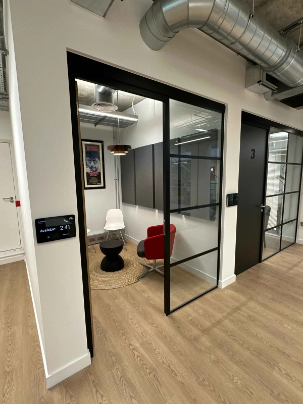 Internal black crittall doors leading to a small private meeting space with modern chairs and an occasional table.