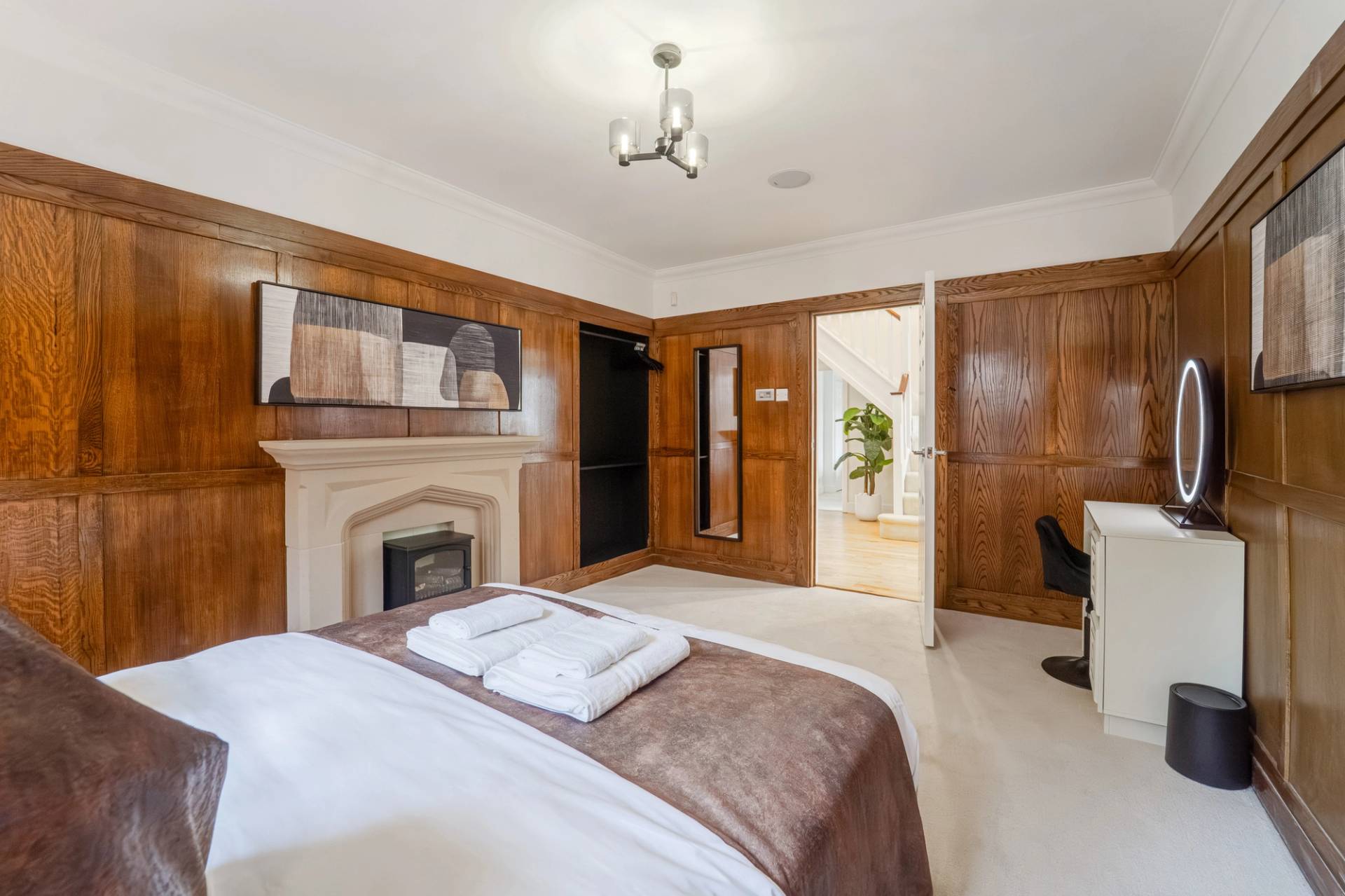 Master suite perspective showing dark wood wall panelling, fireplace, and ensuite door, Love Locations RM11.