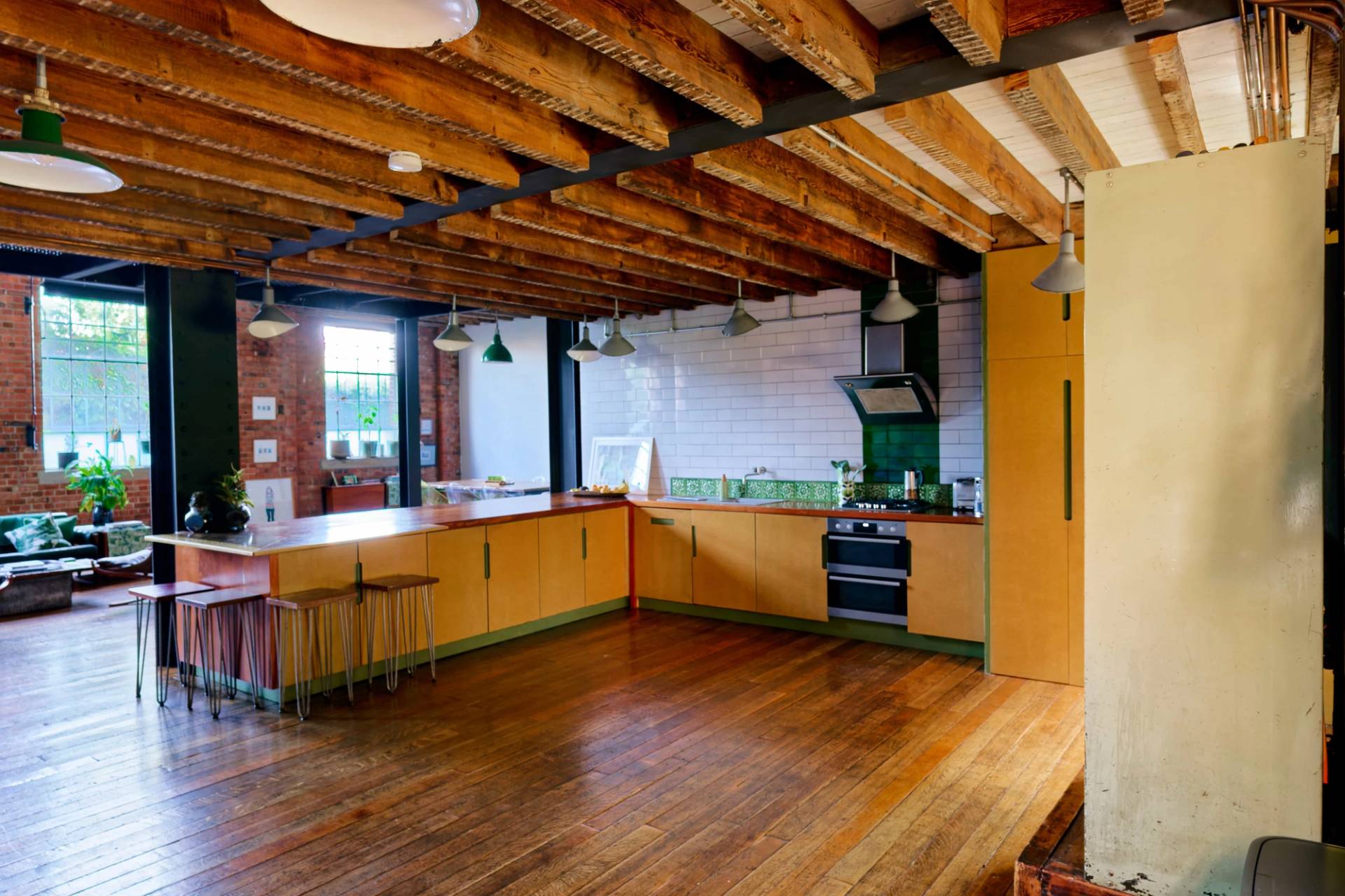 Rustic wooden kitchen island counter with stool seating set under exposed timber ceiling beams in an East London location home, Love Locations E14.