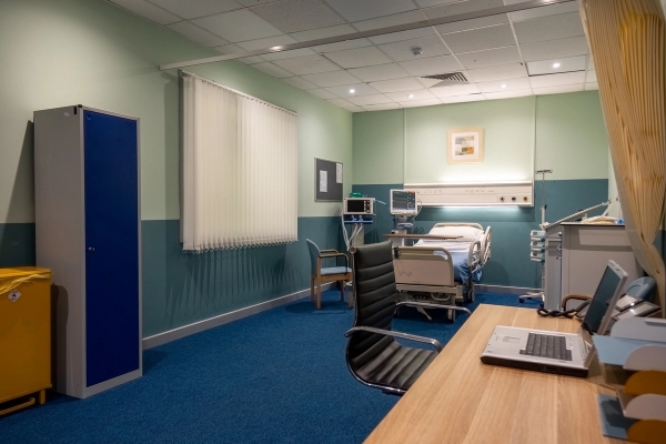 Private hospital patient room featuring a single medical bed, desk, and office chair, Love Locations UB4.