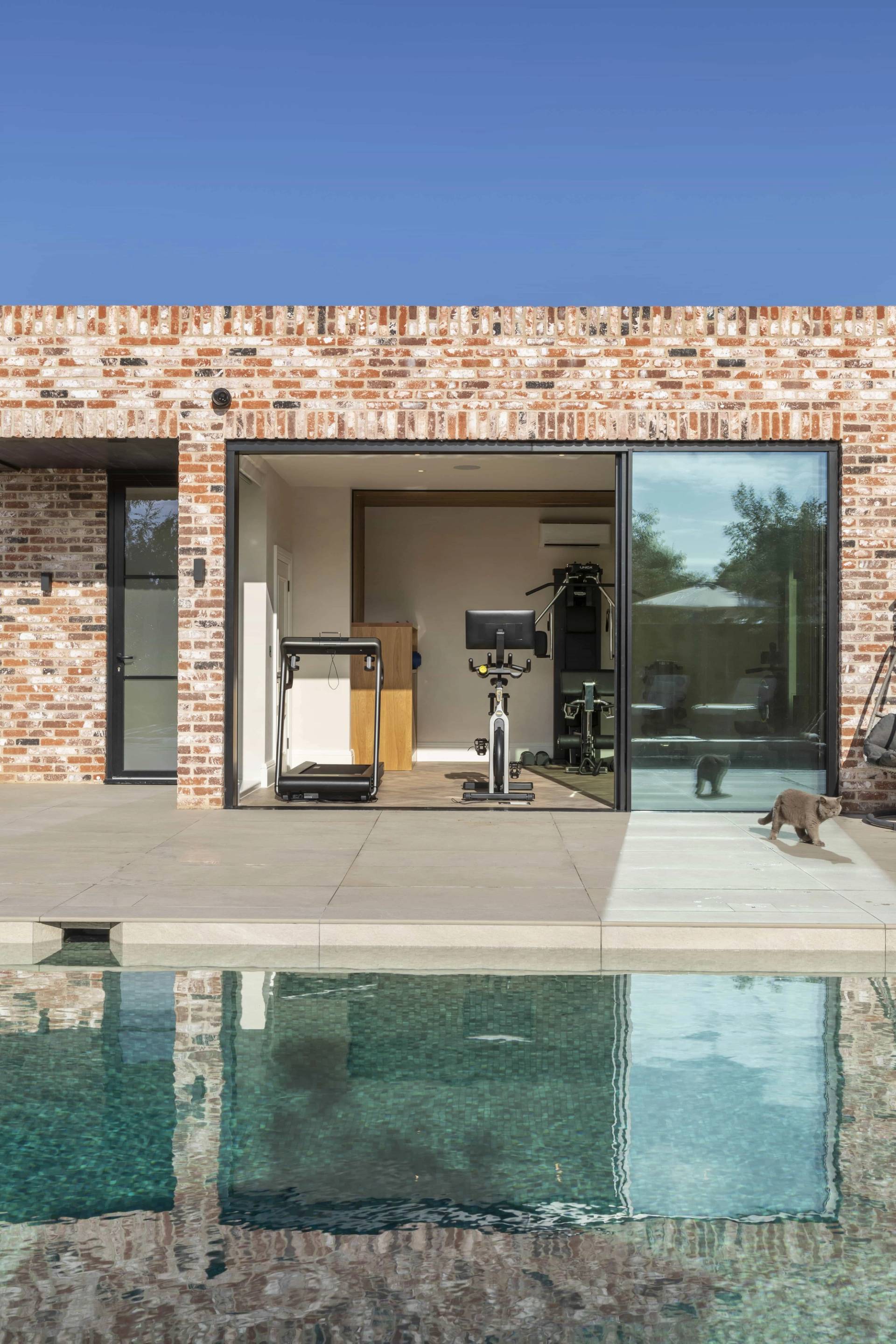 Pool house gym extension with black crittall sliding doors, stationary bike, and treadmill, Love Locations HP18.