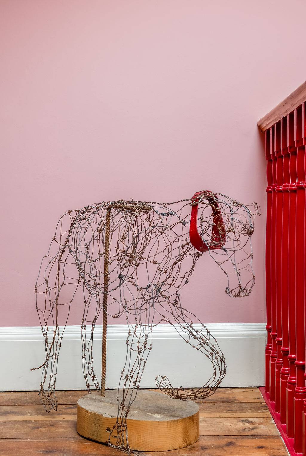 Artistic wire animal sculpture displayed against soft dusty-pink walls in a grand country house hall via Love Locations.