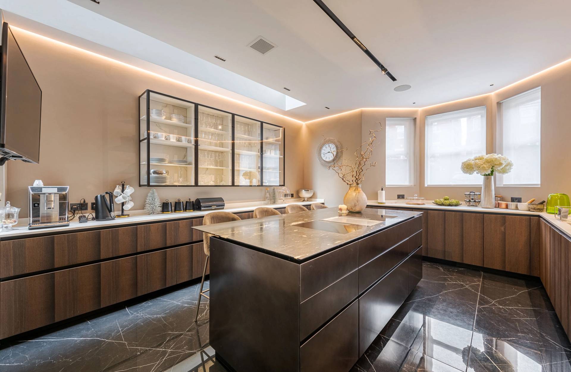 Modern luxury kitchen with dark marble island counter, fluted wood cabinetry, and ambient ceiling lights, Love Locations SW11.