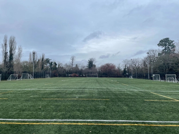 Love Locations synthetic turf location RG30: Ground-level tracking shot across an all-weather football and sports field under an overcast sky, excellent for athletic training scenes.