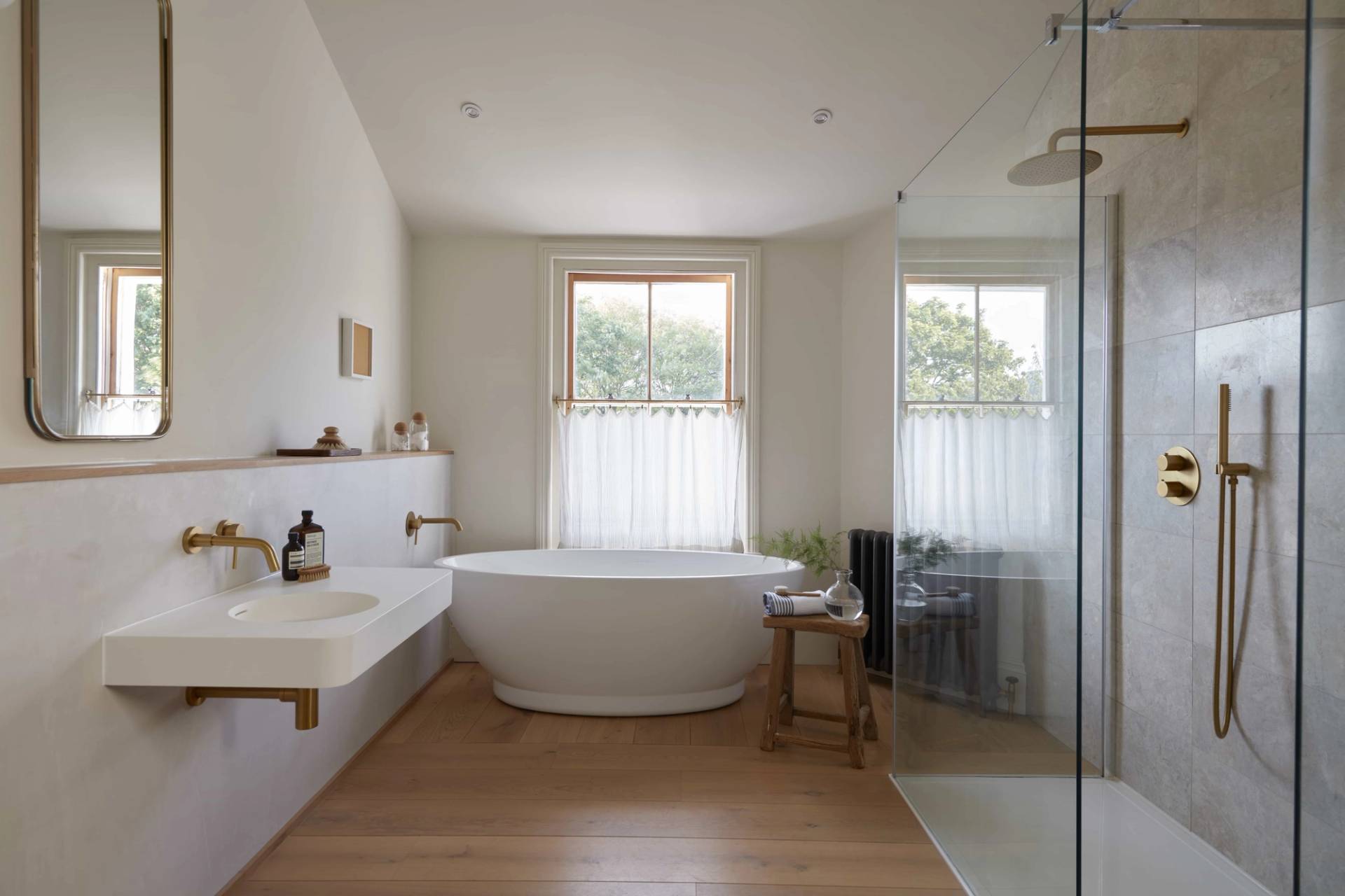 Ensuite bathroom with a white soaking tub set against timber sash windows and sheer linen curtains, perfect for spa product filming, Love Locations.