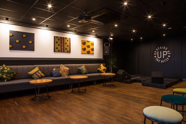 Spacious open floor space with long bench seating, low circular drinks tables, and ambient recessed lighting, ideal for dance rehearsals or event staging, Love Locations SW2.