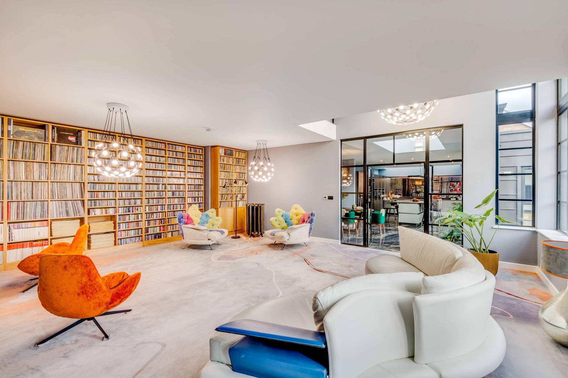 Creative library room with full-height book storage, vibrant accent chairs, and crittall glass room dividers, Love Locations CB2.