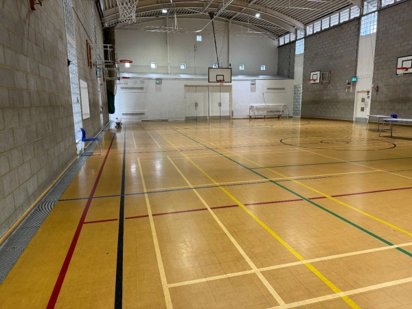 Love Locations large indoor gymnasium film location EN4: Sprawling sports hall with a green boundary line layout and high windows, perfect for high-energy sports commercials and action sequences.