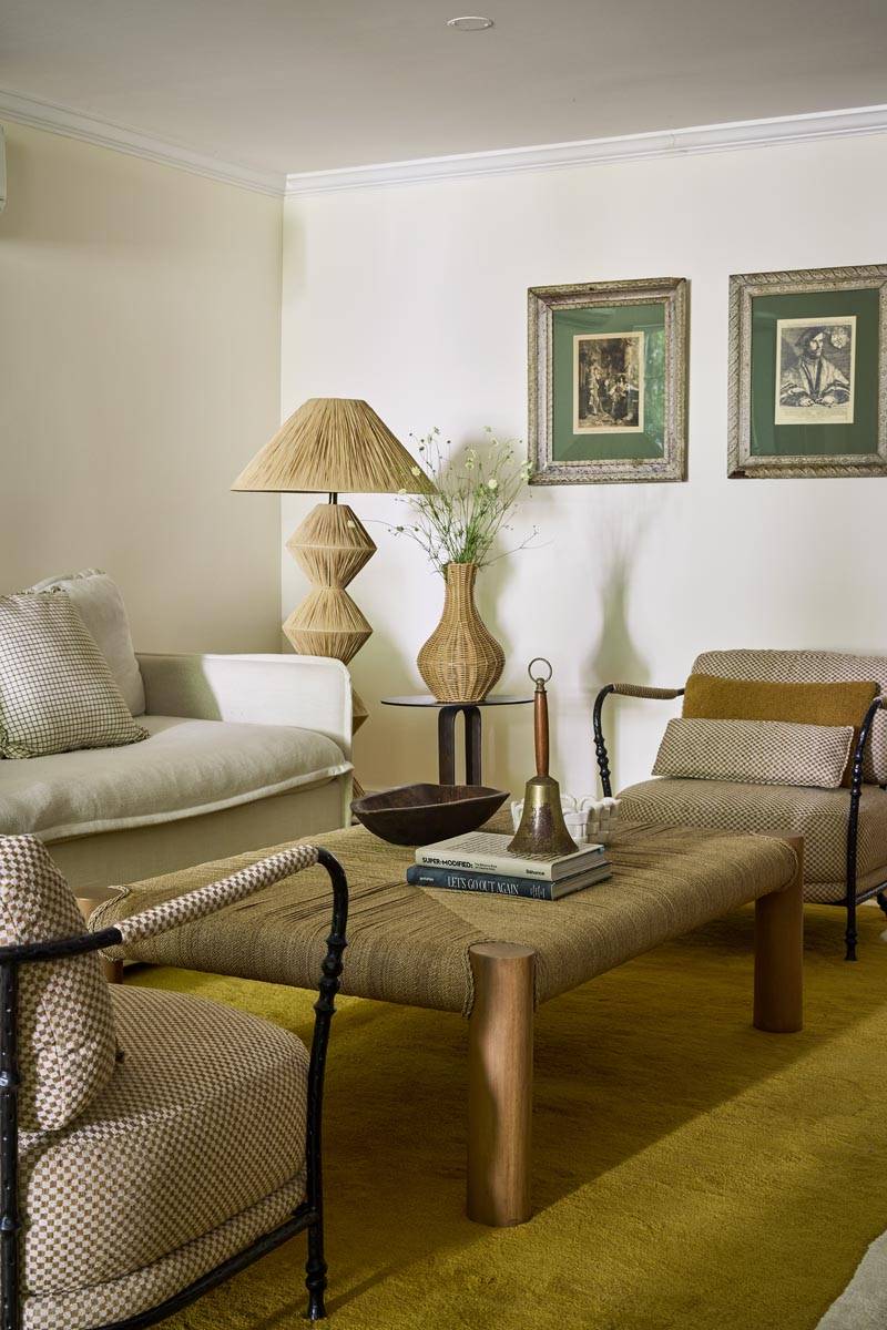 Cozy living room seating area for photoshoot hire in a Manhattan NY 10014 garden-level apartment via Love Locations, showcasing a rattan armchair, textured coffee table, and plaster lamp base.