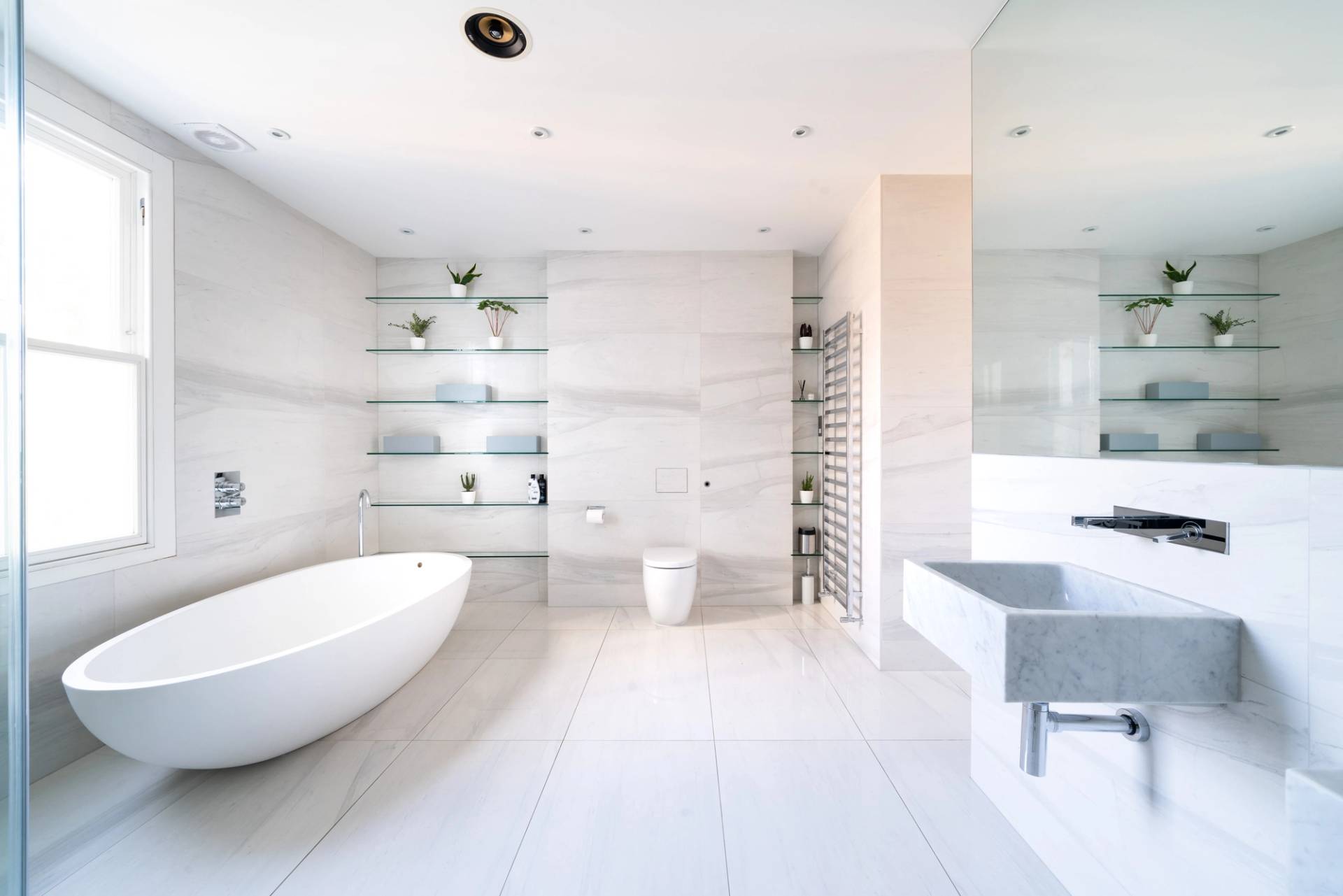 Minimalist bedroom set under sloped loft ceilings with low timber bed frame and natural wood floors, Love Locations SW6.