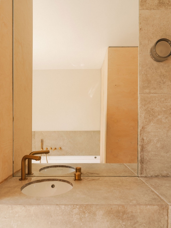 Luxury bathroom vanity setup showcasing modern brass hardware, a circular basin, and smooth stone surfaces, Love Locations.