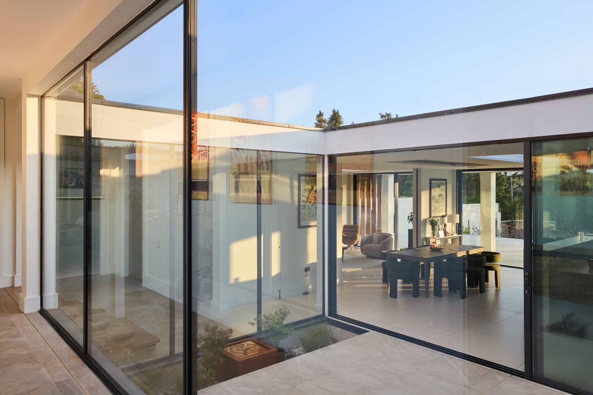 Reflective glass courtyard corridor showing floor-to-ceiling glass windows and modern interior spaces in a Surrey location home, Love Locations KT22.