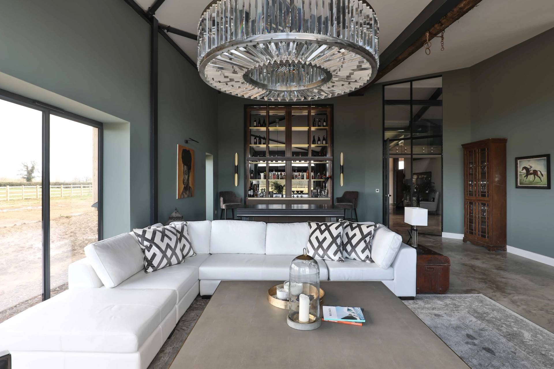 Lounge room featuring a circular crystal chandelier, white velvet corner sofa, and Crittall glass partition doors, Love Locations CV23.