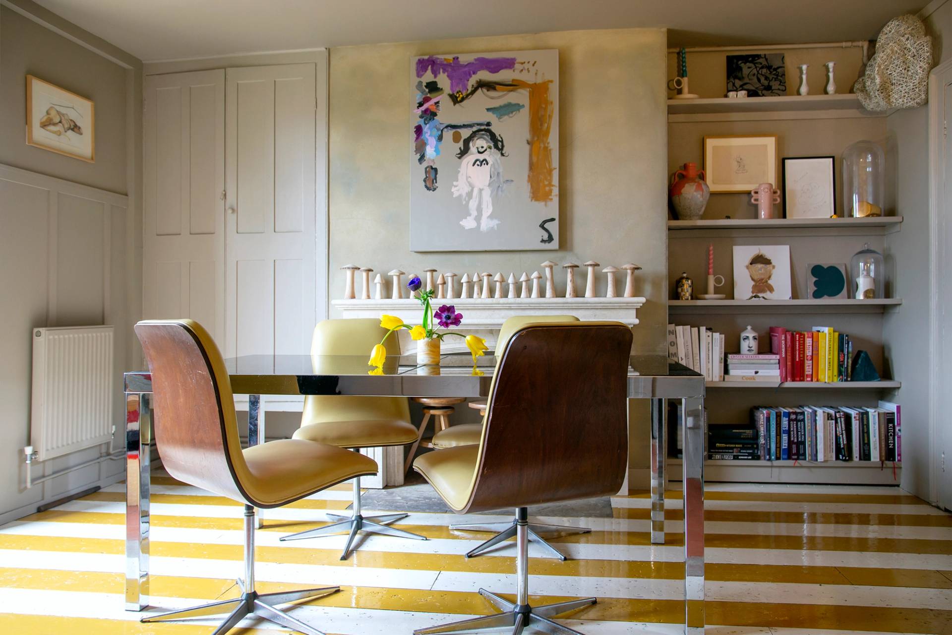 Retro dining room with yellow-and-white striped rug, chrome glass table, and mustard leather chairs, Love Locations ME13.