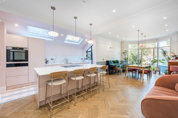 Open-plan Edwardian location house kitchen featuring a light pink island, herringbone wood floors, and modern skylights in Barnet, North London, N11 via Love Locations.
