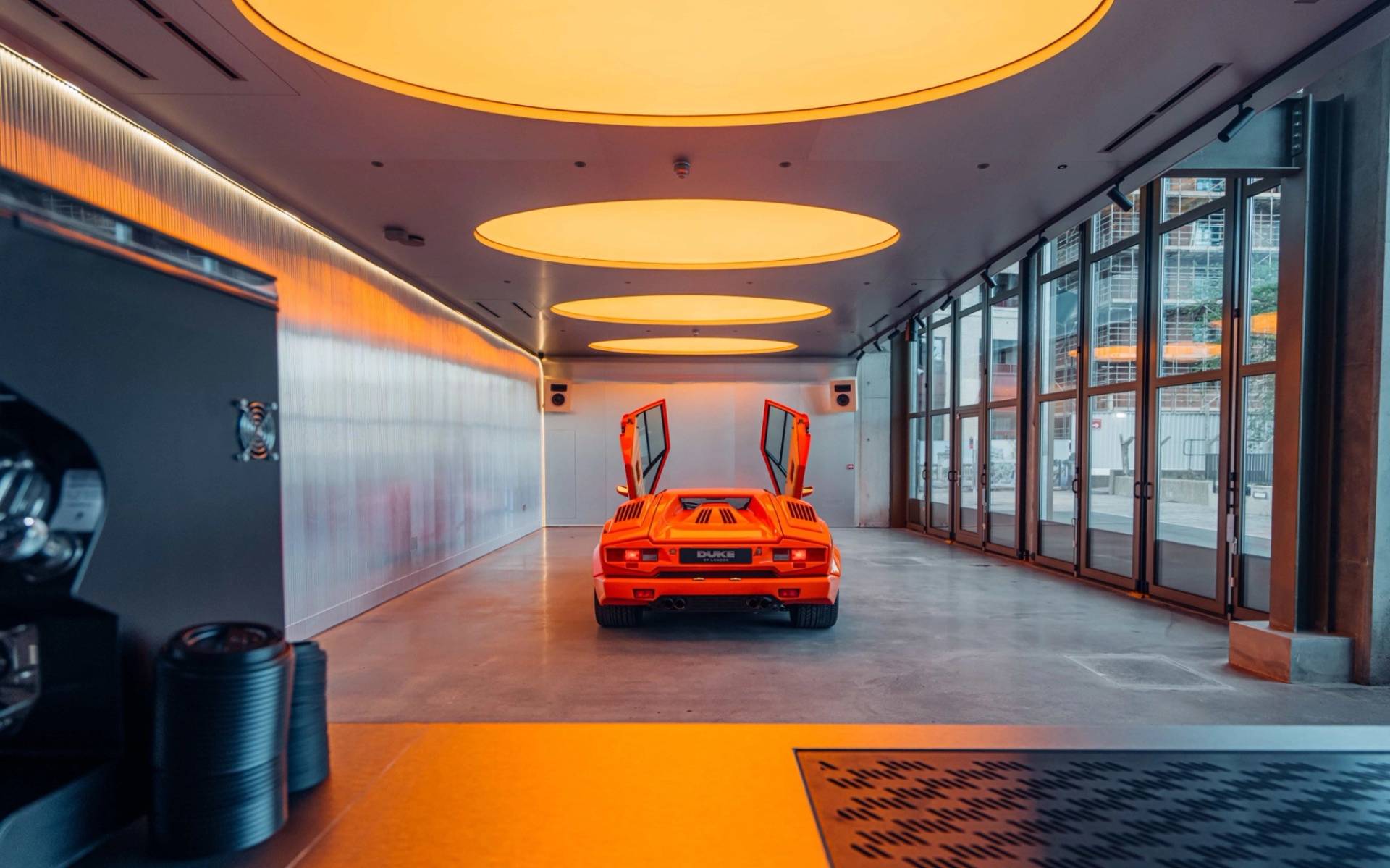 Rear angle showing scissor doors on an orange Lambo supercar in a modern event bar shoot space from Love Locations.