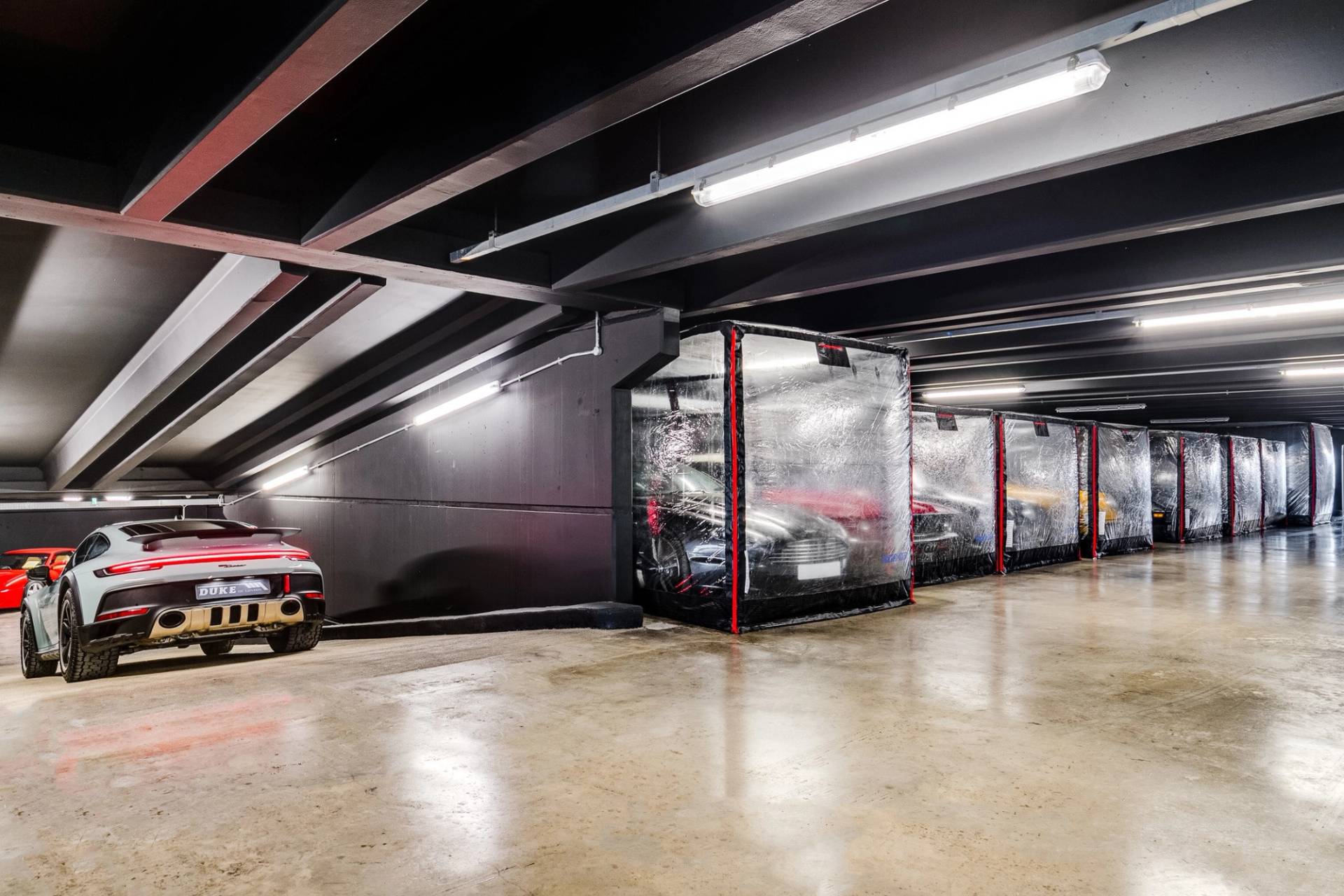Row of luxury sports cars in clear protective bubbles inside a Brentford car showroom by Love Locations.