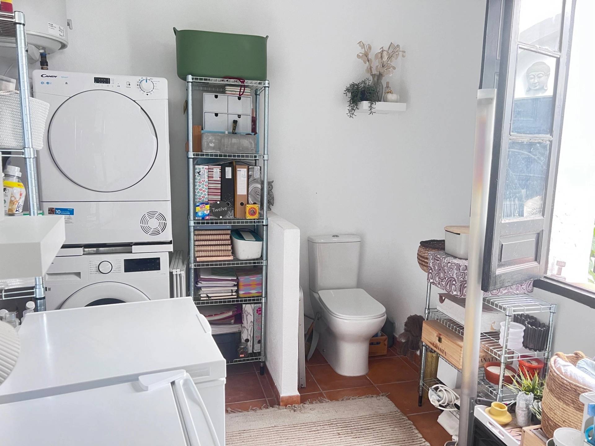 Clean utility room and laundry space location house in Jimena de la Frontera via Love Locations, featuring stacked washer dryer units and minimalist white shelving.