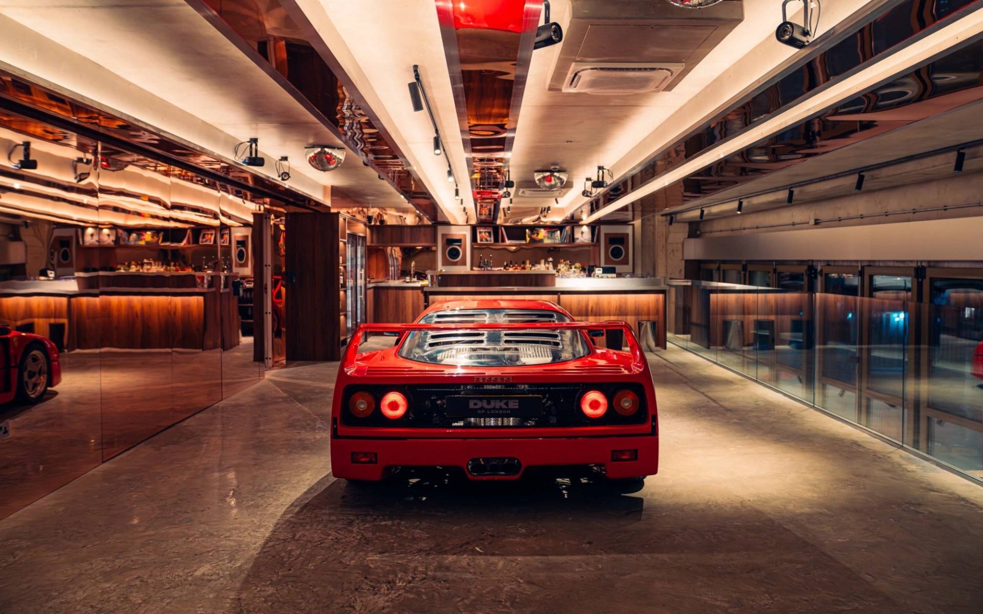 Symmetrical rear view of a red Ferrari F40 inside a luxury automotive listening bar venue by Love Locations.
