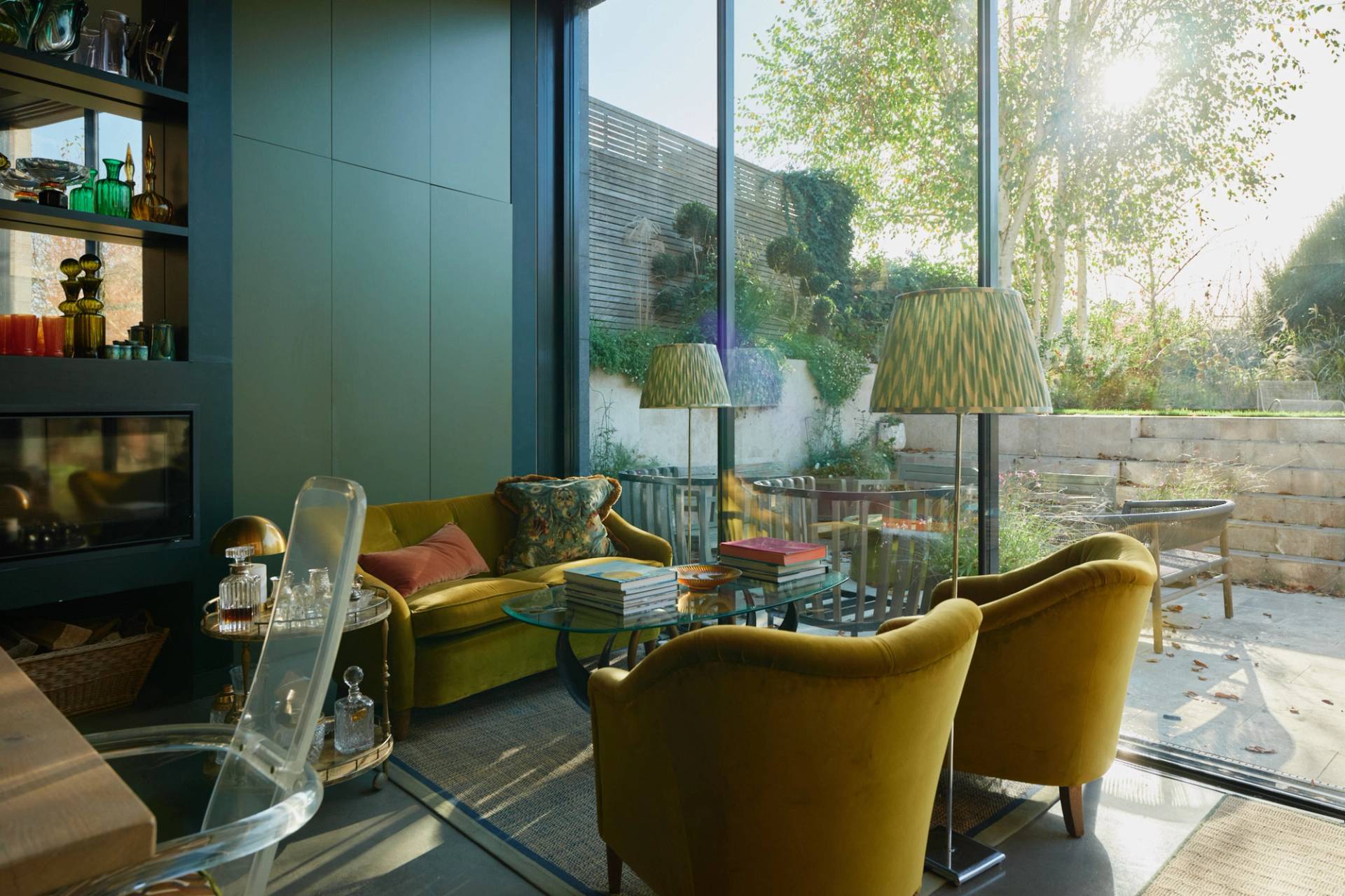 Sunlit lounge area featuring yellow velvet armchairs set beside floor-to-ceiling glass sliding doors, Love Locations.
