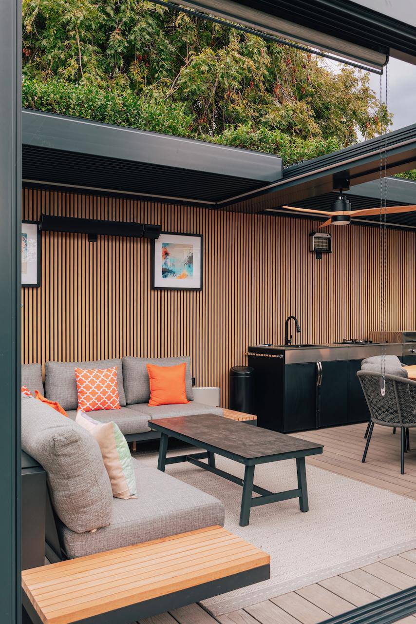 L-shaped outdoor sofa setup inside a luxury garden pergola with slatted timber walls and heating, Love Locations.