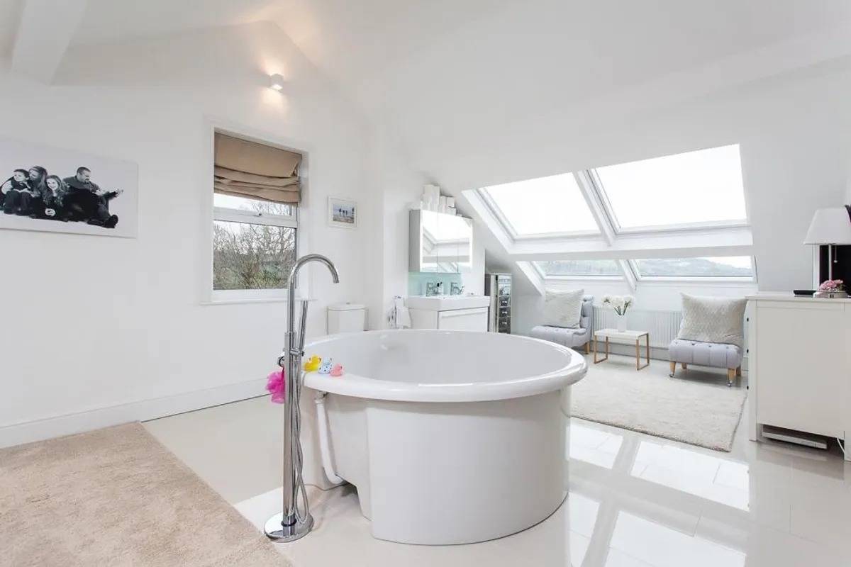 Close-up view of a circular freestanding soaking tub under skylights in an open-plan bedroom suite in Stockport SK6 by Love Locations.
