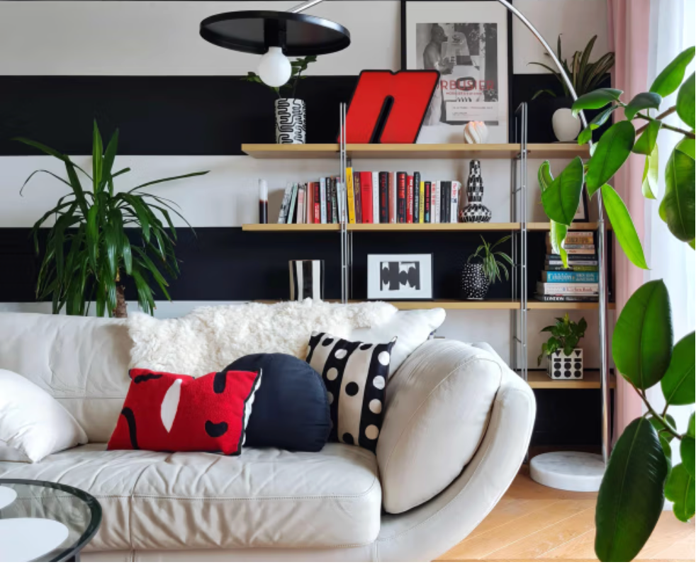 Graphic black and white striped living room at Drakeford with contemporary shelving, plants and colourful accessories.