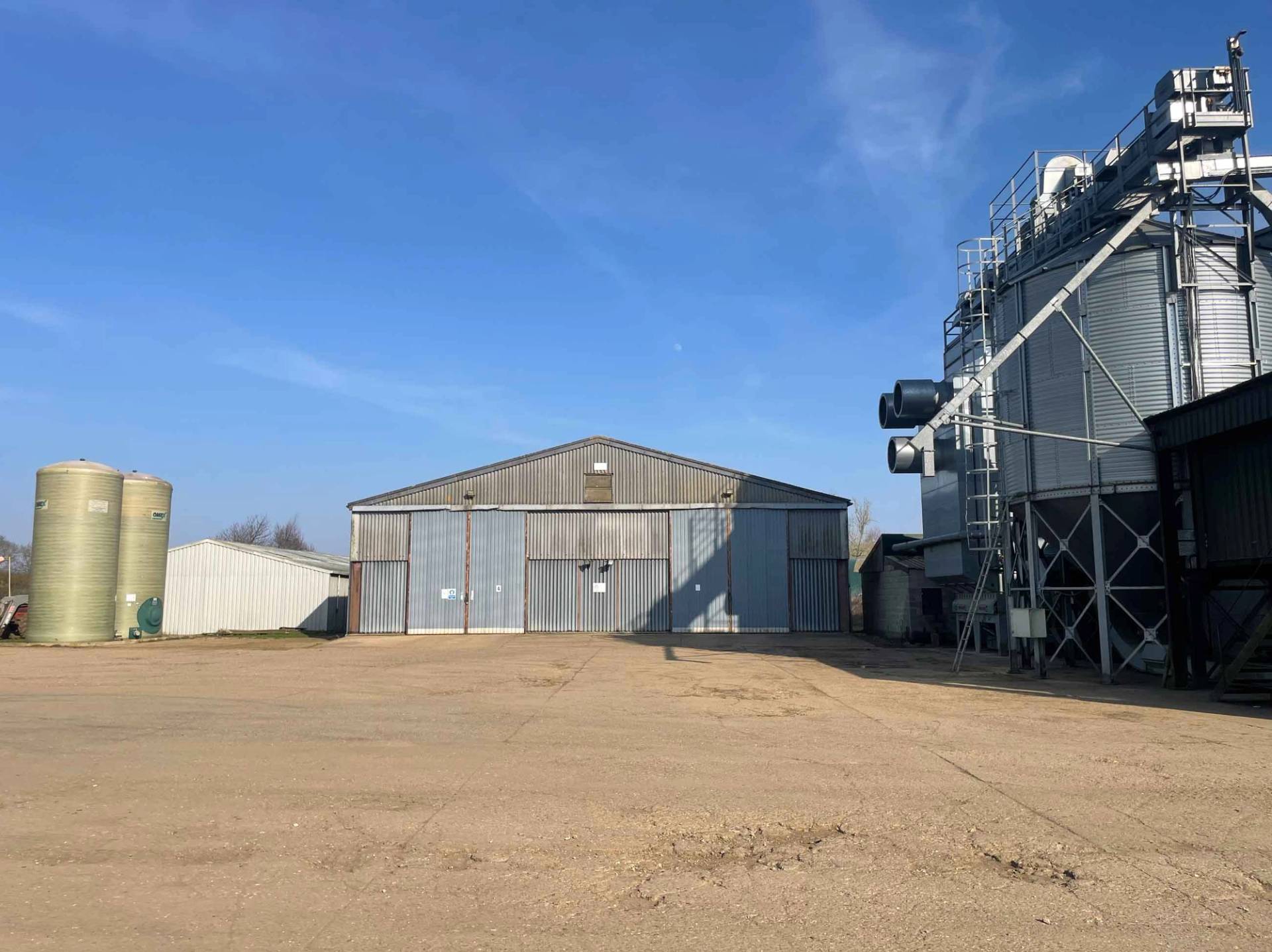 Modern green industrial agricultural warehouse with a secure roller door on a rural estate, Love Locations NN17.