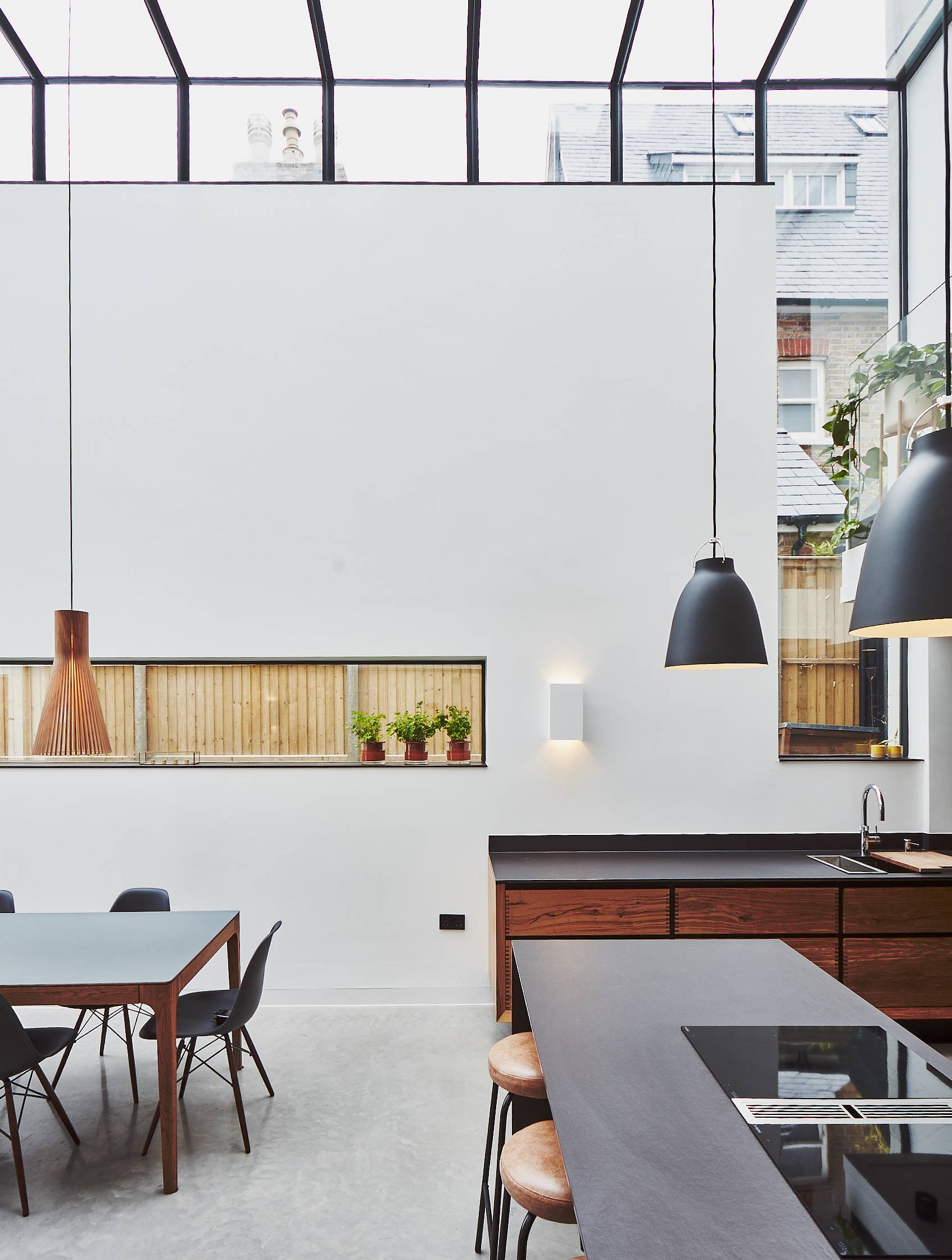 Minimalist white kitchen wall with black pendant lamps, built-in wooden display niche, and polished concrete floor, Love Locations TW1.