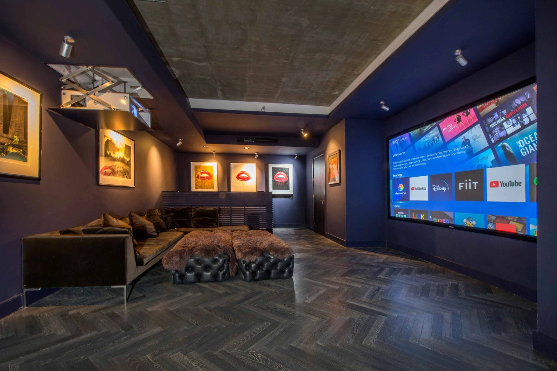 Luxury home cinema and lounge room featuring dark blue walls, a massive projection screen, and comfortable modular seating, Love Locations NW3.