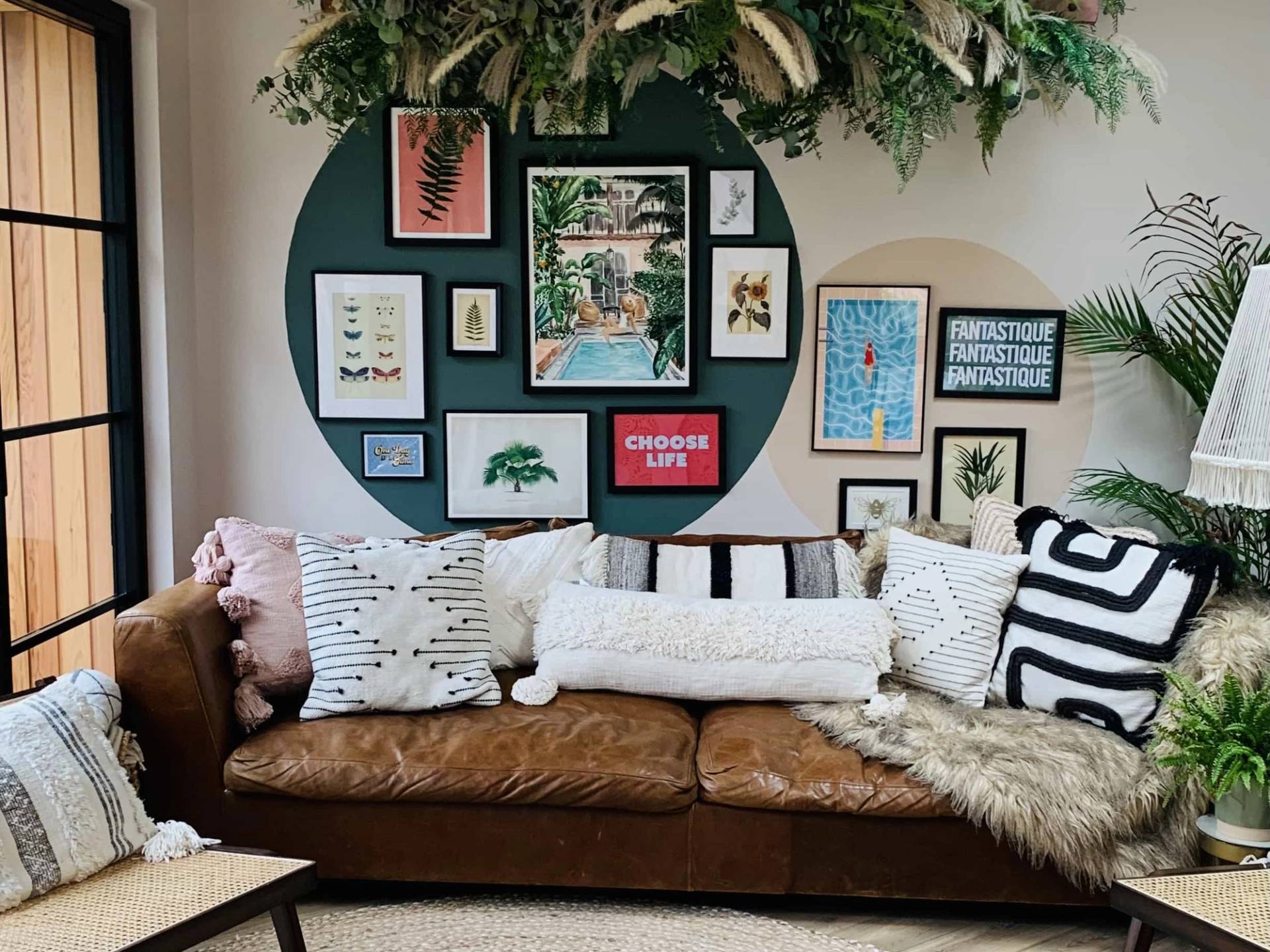 Cozy lounge seating area featuring a brown leather sofa, circular wall art display, and overhead greenery, Love Locations TW11.